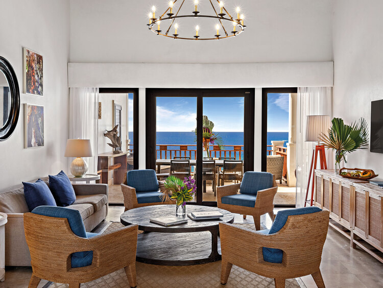 Sala de estar com mesa e cadeiras, TV e vista para o mar da varanda