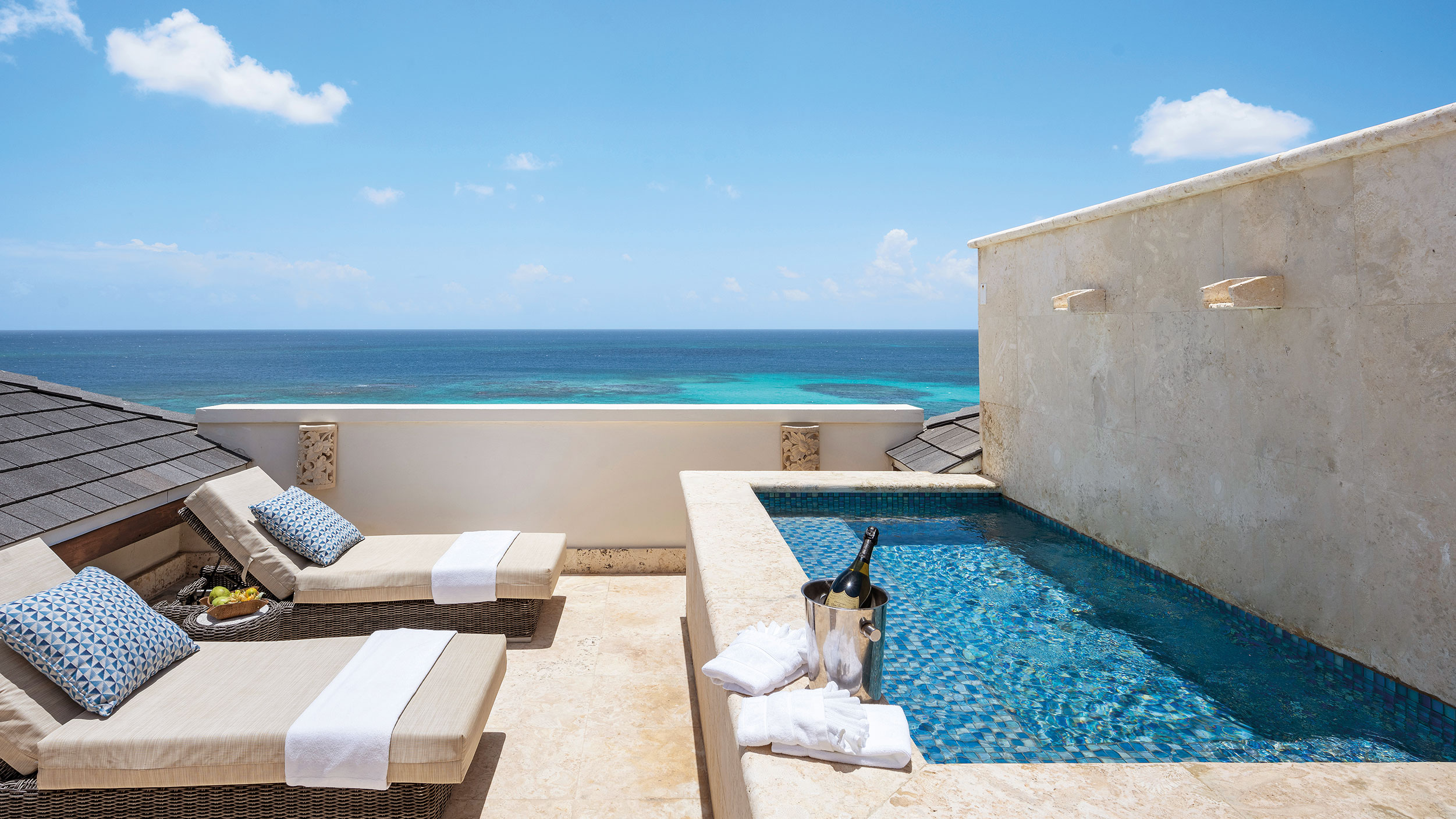 Plunge pool and lounge chairs on balcony overlooking ocean